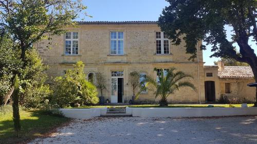 une grande maison en pierre avec un palmier en face de celle-ci dans l'établissement Les Logis de Lestiac, à Lestiac-sur-Garonne