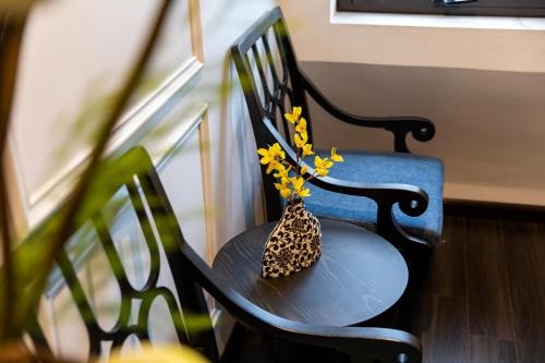 a black chair with a vase with yellow flowers in it at Ha Long Essence Hotel in Ha Long