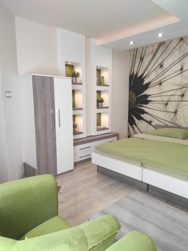 1 dormitorio con 2 camas y silla verde en RP FitLife Stúdió és Vendégház, en Szentgál