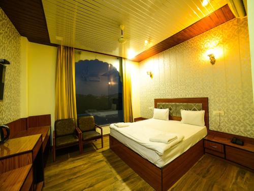 een slaapkamer met een bed, een bureau en een raam bij The Royal Paradise Resort and Salt Yard in Bīr