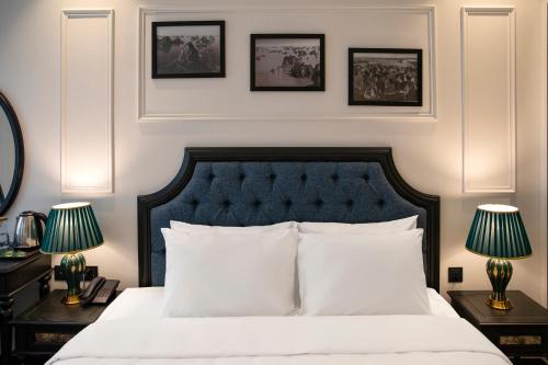 a bedroom with a bed with two lamps and pictures on the wall at Ha Long Essence Hotel in Ha Long