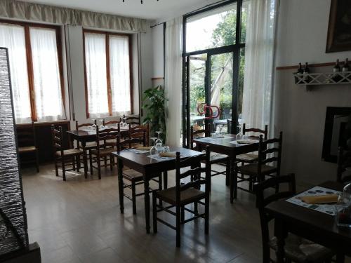 a dining room with tables and chairs and windows at La Locanda di Bivigliano in Bivigliano