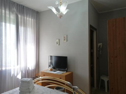 1 dormitorio con 1 cama, TV y ventana en La Locanda di Bivigliano, en Bivigliano