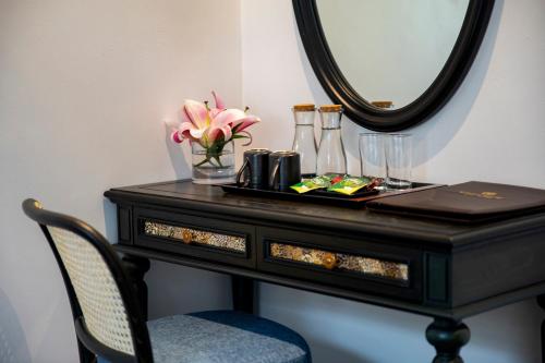 a black dressing table with a mirror and a chair at Ha Long Essence Hotel in Ha Long