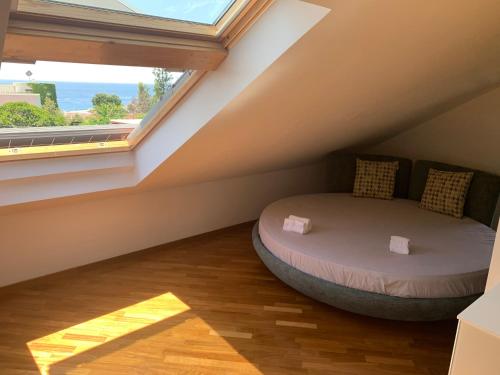a bedroom with a bed in the attic with a window at ALBA SULLO STRETTO in Messina