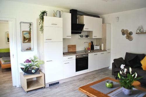a kitchen with white cabinets and a living room at Evia Ferienwohnung in Heimbach