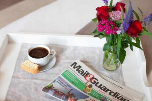 a table with a cup of coffee and a magazine and flowers at Elgin Vintners Country House in Elgin