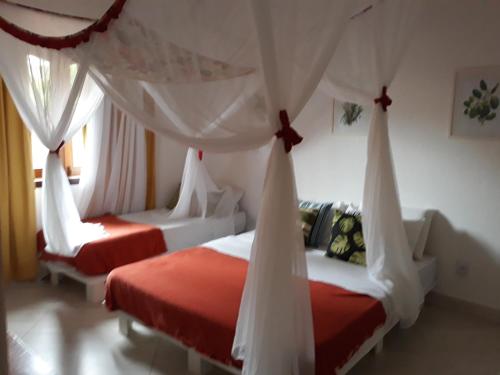 1 dormitorio con 2 camas con cortinas en Casa Luxo Frente ao Mar en Arraial d'Ajuda