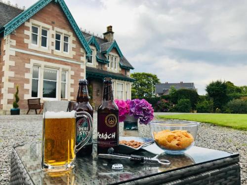a table with two bottles of beer and a bowl of food at Lairds Lodge Inverness in Inverness
