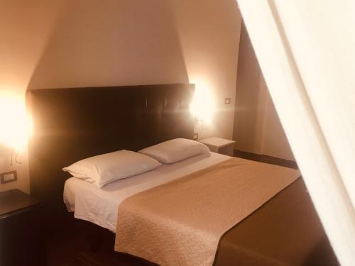 1 dormitorio con 1 cama con 2 almohadas blancas en B&B La Storia Di Napoli, en Nápoles