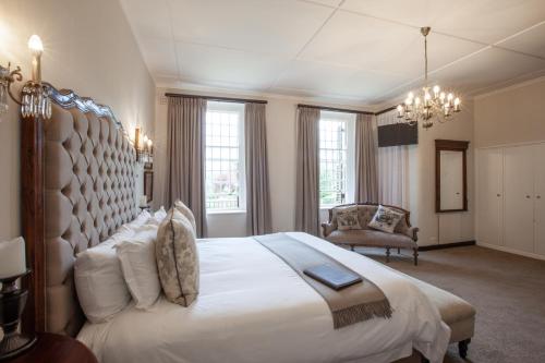 a bedroom with a large white bed and a chair at Elgin Vintners Country House in Elgin