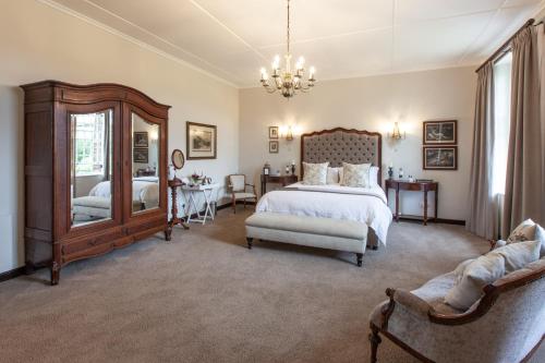 a bedroom with a bed and a chair and a mirror at Elgin Vintners Country House in Elgin