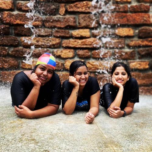 three women laying on the ground in front of a fountain at Marutham Village Resort in Mahabalipuram