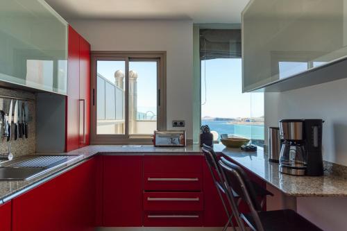a kitchen with red cabinets and a large window at Penthouse with Private Swimming Pool in Melenara