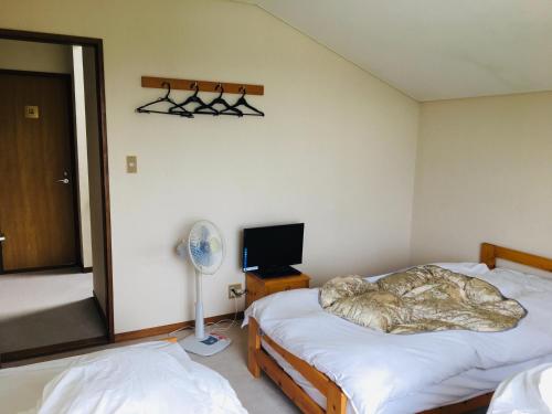 a bedroom with two twin beds and a fan at Hotel Radish House in Senboku