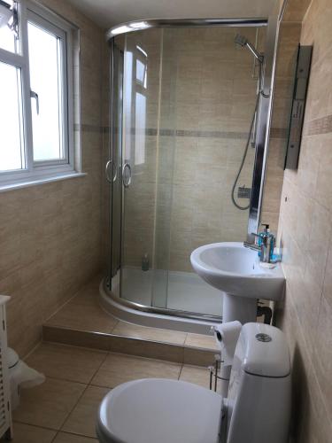 uma casa de banho com um chuveiro, um WC e um lavatório. em Carlton Guest House em Stratford-upon-Avon
