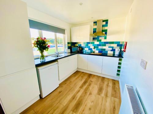 a kitchen with white cabinets and a vase of flowers at Driftwood Seagrass in Par