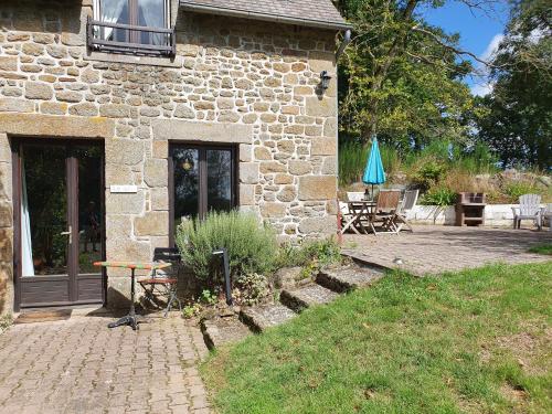 a stone house with a patio and a table and chairs at Le Grand Domaine du Rocher in Bonnemain