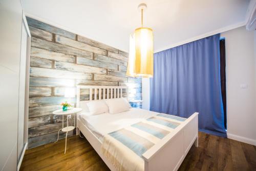 a bedroom with a white bed and a wooden wall at Villa Ina & Eva Bayview Deluxe in Burgas City