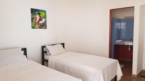 a room with two beds and a painting on the wall at Le Petit Quartier "Chez Amanthia" in Cap Skirring