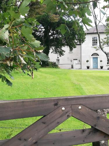 a wooden bench in front of a house with a yard at Next door at Broomfield House in Midleton