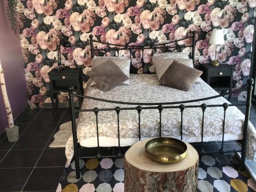 Un dormitorio con una cama con flores en la pared. en La Roséa, en Mende