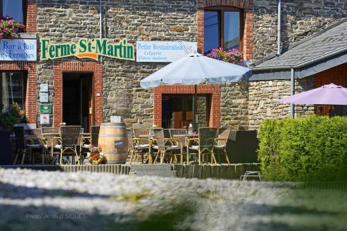 a brick building with tables and chairs and umbrellas at ferme st martin in Manhay