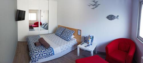 una piccola camera con letto e sedia rossa di LauRina - Chambre, SDB, terrasse, arrivée autonome a Royan