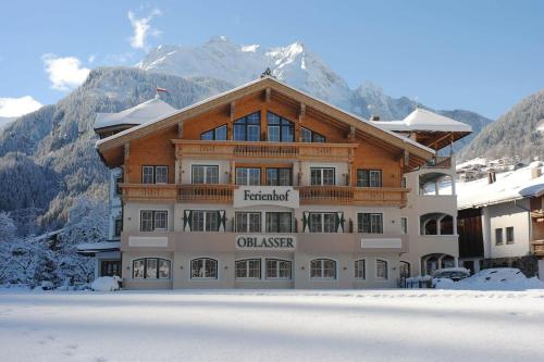 un gran edificio en la nieve con una montaña en Ferienhof Oblasser en Mayrhofen