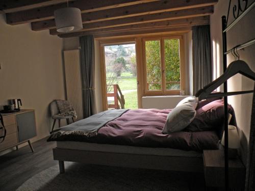 a bedroom with a bed in front of a window at Le Pré in Juriens