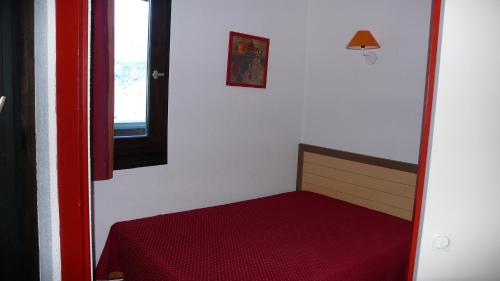 a small bedroom with a red bed and a window at LES MENUIRES REBERTY in Les Menuires