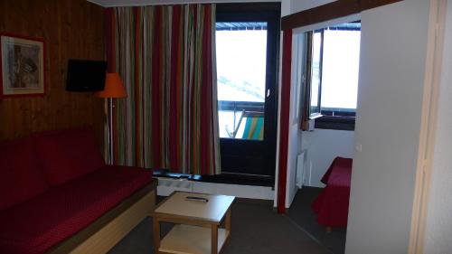 a living room with a red couch and a window at LES MENUIRES REBERTY in Les Menuires