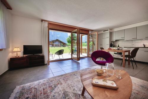 a living room with a table and a kitchen at Apartment Trümmelbach, Comfortabl & Cozy, Private Terrace with best views in Lauterbrunnen