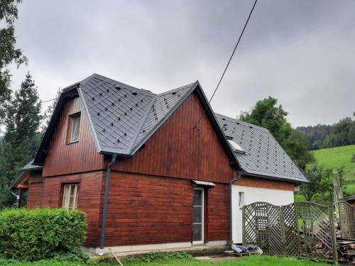 une grange rouge avec un toit noir dans l'établissement Beba, à Heřmanovice