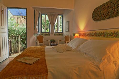 a bedroom with a large white bed and windows at Pouso Caminho das Artes in Cunha