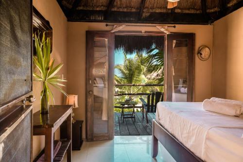 a bedroom with a bed and a door to a patio at Playa Esperanza Tulum in Tulum