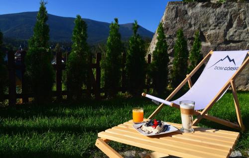 a chair with a plate of food and two glasses of orange juice at Dom Górski in Karpacz