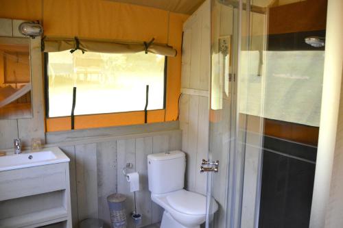 a small bathroom with a toilet and a sink at Modern Nomads in Thenon