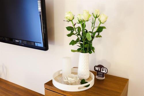 a white vase with white roses in it on a shelf at Villa Aina Boutique Hotel in Laško