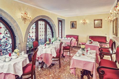a restaurant with tables and chairs with pink tablecloths at Hotel Firenze in Venice