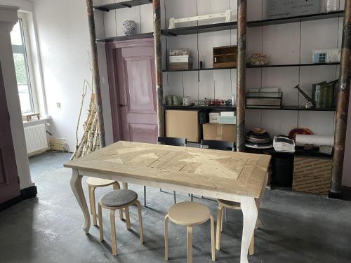 a table with four stools in a room with shelves at Bed & Breakfast Bloemen Vertellen in Elst