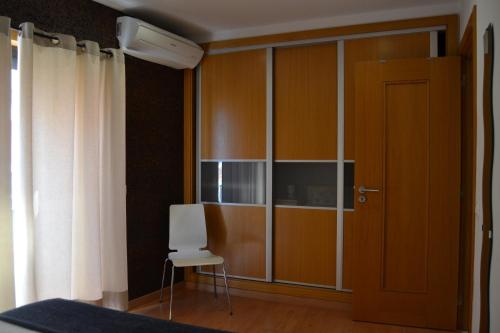 a room with a closet with a white chair and a door at Cerca da Vitória 1 Sesimbra in Sesimbra