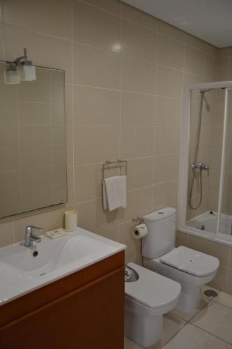 a bathroom with a sink and a toilet and a mirror at Cerca da Vitória 1 Sesimbra in Sesimbra
