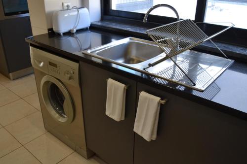 a kitchen with a sink and a washing machine at Cerca da Vitória 1 Sesimbra in Sesimbra