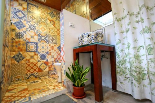 a bathroom with a tiled wall and a plant at Windhouse B&B in Tainan