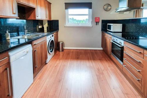 a kitchen with wooden cabinets and a wooden floor at Hilton Wynd Apartment in Rosyth