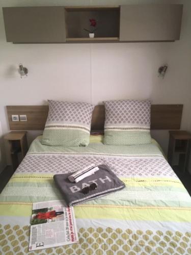 Una cama con un libro y una revista. en Mobil home excellence le lac des rêves 4* LATTES, en Lattes