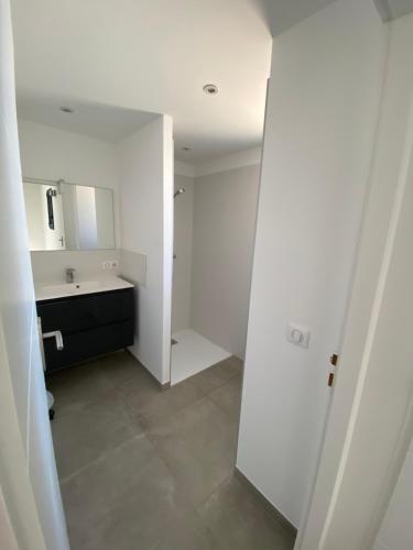 une salle de bain blanche avec un lavabo et un miroir dans l'établissement Villa Mamago, à Cirendinu