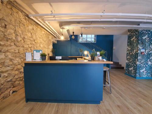 un bureau avec un comptoir bleu et un mur en pierre dans l'établissement Brit Hotel Bordeaux Arena, à Latresne