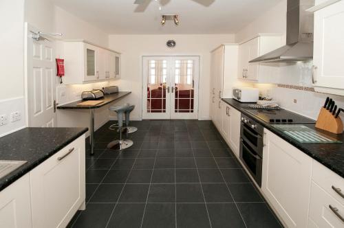 a kitchen with white cabinets and black tile floors at Cunard Apartments in Douglas